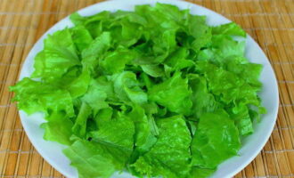 Подготовить блюдо для подачи салата – оно должно быть довольно широким, но не глубоким. На него выложить вымытые целые листья салата.