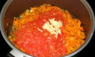 В сковороду к зажарке добавьте томаты (или уже готовый томатный соус), а также рубленый чеснок, соль и приправы по вкусу.