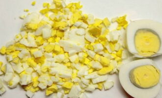 Отваренные вкрутую и остывшие вареные яйца нарежьте яйцерезкой или ножом на кубики, добавьте в Оливье.