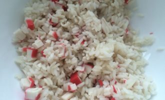 Далее по рецепту крабового салата, сварите до полной готовности в подсоленной воде нужное количество риса. Охладите его и переложите в салатницу.