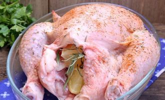 Внутрь курицы вложите целую веточку розмарина, лимоны и равномерно распределите все это внутри.