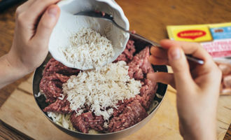В последнюю очередь положите в миску с ингредиентами фарш и рис, с которого не нужно сливать воду. Всыпьте немного соли и перца, а затем тщательно вымесите фарш из ваших ингредиентов. Все должно стать однородным.
