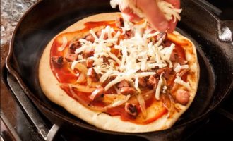 Основу для пиццы смазать соусом, выложить по всей поверхности начинку. Накрыть крышкой и на среднем огне готовить еще 4-5 мин., пока сыр не расплавится.