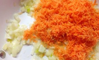 Морковь потереть на мелкой или средней терке, выложить обжариваться на сковородку к луку.