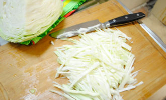 Нашинкуйте тонкой соломкой часть кочана капусты. Мелко нарезанная капуста готовится быстрее.