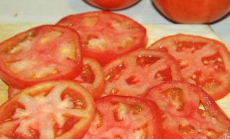 Оставшиеся томаты нарежьте на такие же кружки, как и баклажаны. Работайте очень острым ножом, иначе серединка у спелых томатов может выпасть, а этого допускать нельзя.
