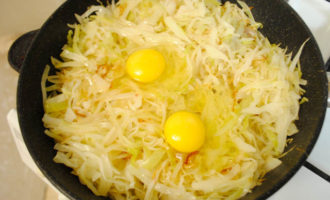 В обжаренную капусту вбейте два яйца. Можно яйца сварить заранее, нашинковать и добавить к капусте. Но с сырыми яйцами быстрее.