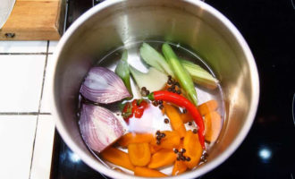Чтобы приготовить заливное из судака, для начала необходимо сварить овощной бульон. В кастрюлю складываем крупно нарезанные лук, морковь, сельдерей, стебли петрушки, специи, заливаем водой и ждем пока он закипит. Варим бульон на медленном огне, степень готовности определяем по состоянию моркови.