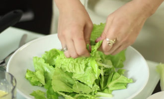 Дно блюда устелить порванными листьями салата, поверх него разложить курицу и сыр.