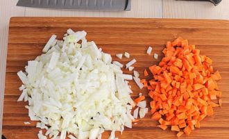 Лук с морковью очистите и затем нарежьте при помощи острого ножа на маленькие кубики. Вместо этого вы также можете натереть корнеплоды на терке.