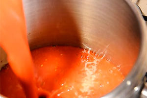 Зрелые помидоры заранее промыть, сделать надрезы крест-накрест. Залить томаты кипятком, подержать так 3-4 мин., затем быстро переложить в ледяную воду и снять кожицу. Порезать помидоры на дольки, пробить блендером или перекрутить на мясорубке. Вылить получившуюся массу в кастрюлю.