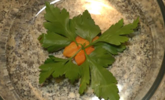 Сваренную морковь порежьте на красивые фигурки и уложите в посуду, в которую будете наливать холодец. Положите также 4–5 листков зеленой петрушки, чтобы было красиво.