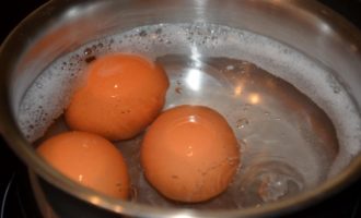 Яйца сварить вкрутую, для этого залить их водой в сотейнике, подсолить, можно в воду добавить щепотку соды. Отваривать яйца после закипания ровно 10 мин., затем быстро шумовкой переложить в ледяную воду и дать остыть. Картофель вместе с морковью сварить в одной кастрюле, не очищая. С горошка слить воду, откинуть его на сито, чтобы вся влага ушла. Отвесить на весах 100 г.