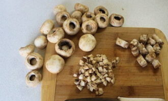 Чтобы приготовить фаршированные шампиньоны в духовке с сыром, для начала подготовьте грибы. Их нужно тщательно промыть в проточной воде, а затем срезать ножки максимально близко к основанию шляпки.