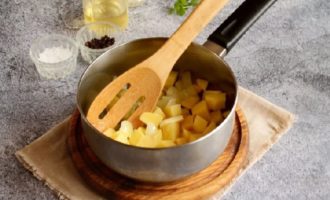 Поместите на плиту сотейник с толстым дном, добавьте в него растительное либо оливковое масло и начните разогревать. В это время нарежьте помельче лук и нарежьте кубиками либо брусочками клубни картофеля. Сначала положите в сотейник лук, а спустя минуту – картофель. Затем добавьте предварительно измельченный при помощи чесночного пресса чеснок. Перемешайте ингредиенты и обжаривайте около минуты на медленном огне.