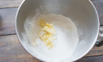 В чашу миксера либо удобную миску добавьте просеянную муку и кукурузный крахмал, чтобы начать делать тесто. Туда же добавьте разрыхлитель, сливочное масло и яйца.