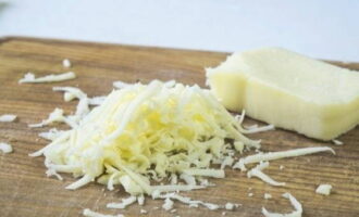 Затем нужно подготовить начинку для грибов. Для этого натрите на мелкой терке выбранный сыр, который не будет течь (сулугуни или пармезан – идеальный выбор). 