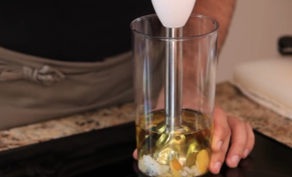 В стакан налейте 150 мл оливкового масла и положите в него яйцо, которое варилось не больше 1 минуты. Затем погружным блендером, не отрывая его от дна стакана, взбейте.