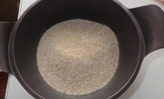 Промытую пшеничную крупу выложите в кастрюлю с толстым дном, либо в  эмалированную кастрюлю, а затем добавьте один стакан чистой воды. Крупу в кастрюле доведите до кипения на большом огне.