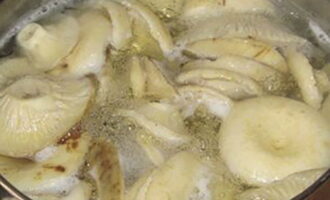 В большую эмалированную кастрюлю поместите грибы, залейте их водой, всыпьте 2 столовые ложки соли. Доведите содержимое кастрюли до кипения и варите 15-20 минут.