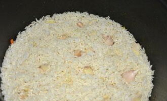 Чеснок очистите от шелухи и промойте в холодной воде. Сделайте небольшие углубления в рисе и поместите в них очищенный чеснок.