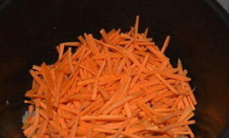 Морковь тщательно вымойте, а затем очистите от кожуры с помощью овощечистки. Очищенную морковь нарежьте тонкой соломкой и выложите в чашу прибора к обжаренному луку, хорошо перемешайте и обжарьте до золотистого цвета.