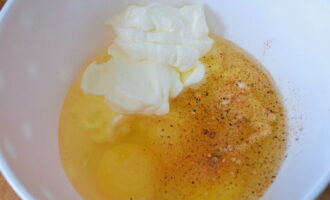 В миску разбиваем яйца, добавляем сметану, соль и черный молотый перец по вкусу. Вилкой взбалтываем все компоненты, пока не получится однородная смесь. 