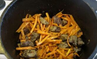 Очищенную морковь нарежьте тонкой соломкой. К этому времени мясо равномерно обжарится. В казан к мясу выложите нарезанную морковь и обжарьте, периодически помешивая, до золотистого цвета.