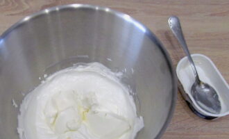 Вводим сливочный сыр. Кладем в сливочную массу по одной-две ложке сливочного сыра и взбиваем крем до однородности. Таким образом добавляем все количество сыра.