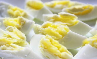 Яйца варим до твердого желтка – это займет одиннадцать-двенадцать минут. Остужаем их, очищаем и нарезаем аккуратными продольными четвертинками.