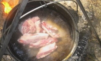 Мясо свинины можно брать любое: филе или на косточке. Погружаем продукт в казан, солим, добавляем специй и устанавливаем на костер.