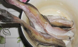 Для того, чтобы приготовить минтай в кляре, заранее размораживаем рыбу. Срезаем чешую, головы и хвосты. Подготовленный продукт промываем в холодной воде.