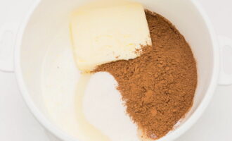 В молоко кладем мягкое сливочное масло, насыпаем сахар и какао. 