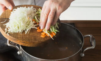 Когда курица готова, выкладываем ее на тарелку для остывания. В бульон погружаем измельченные овощи.