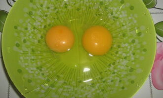 Отдельно в тарелку разбиваем два куриных яйца.