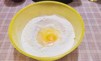 В миску просейте часть муки и одну чайную ложку соли, разбейте яйцо, влейте растительное масло и воду.