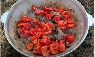 Далее в казан переложить крупно нарезанный очищенный болгарский перец и пожарить еще 10 минут. Овощи при жарке периодически помешивать.