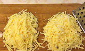 Сыр натрите на крупной терке и разделите на две равные части.