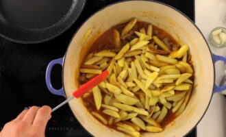 Чистим картофель и также режем тонкой соломкой. Добавляем продукт в блюдо, заливаем стаканом воды и тушим.