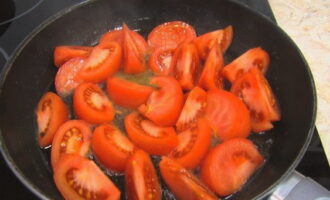 Глубокую сковороду хорошо разогрейте на сильном огне. Налейте небольшое количество растительного масла, а затем выложите нарезанные помидоры.