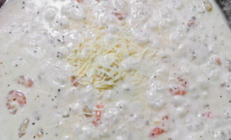 Сыр «Пармезан» натрите на мелкой терке и добавьте в сковороду к креветкам. Тальятелле откиньте на дуршлаг.