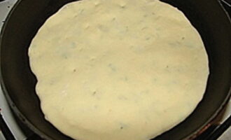 Теперь необходимо раскатать этот шарик в тонкую лепешку, чтобы через тесто начали просвечиваться сыр и зелень. Положите лепешку на сухую разогретую сковородку, в нескольких местах проткните лепешку вилкой.
