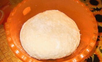 Замешиваем плотное тесто на чебуреки. Для этого необходимо просеять муку, добавить в ней теплую воду, яйцо, растопленное масло, соль и тщательно все перемешать.