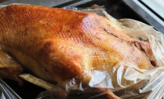 Через 1,5 часа достаньте гуся, аккуратно разрежьте пакет и полейте птицу выделившимся жиром. Верните гуся в духовку и запекайте его еще 30 минут.