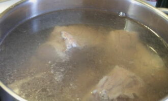 Кусочки сырой говядины выкладываем в большую кастрюлю и заливаем их водой. Ставим на плиту до кипения.
