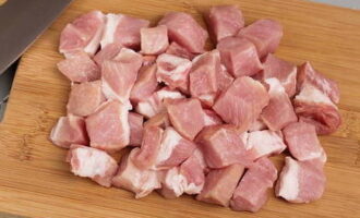 Чтобы приготовить бигус из свежей капусты, свинину промываем, чистим мясо от белых прожилок и нарезаем небольшими кубиками.