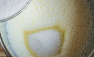 Сахар смешать с ванилином и постепенно соединить его с яично-молочной смесью до полного растворения сыпучих ингредиентов. 