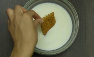 Печенье поштучно окунаем в отдельную миску с молоком и выкладываем слоем близко одно к одному на отдельное блюдо. 