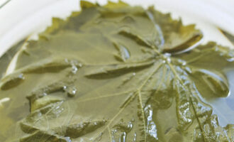 Виноградные листья помойте и залейте кипятком на 5-7 минут. Затем откиньте листья на дуршлаг, чтобы стекла вода. Удалите с листьев черешки.