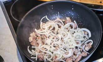 Лук очистите от шелухи и нарежьте полукольцами. Добавьте лук к мясу на сковороду, посолите и продолжайте жарить до мягкости лука.